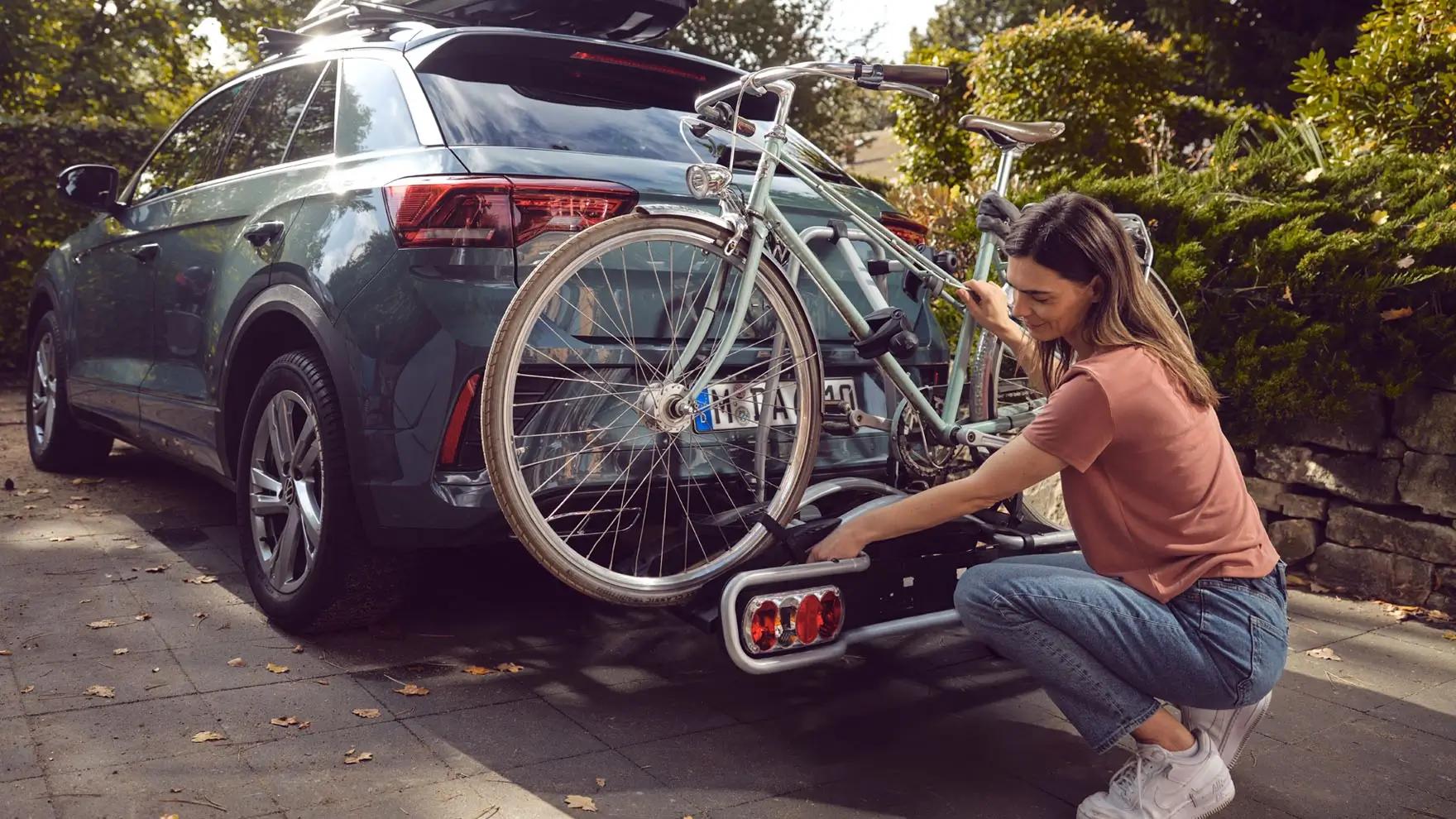 frau-befestigt-fahrradtraeger-am-auto